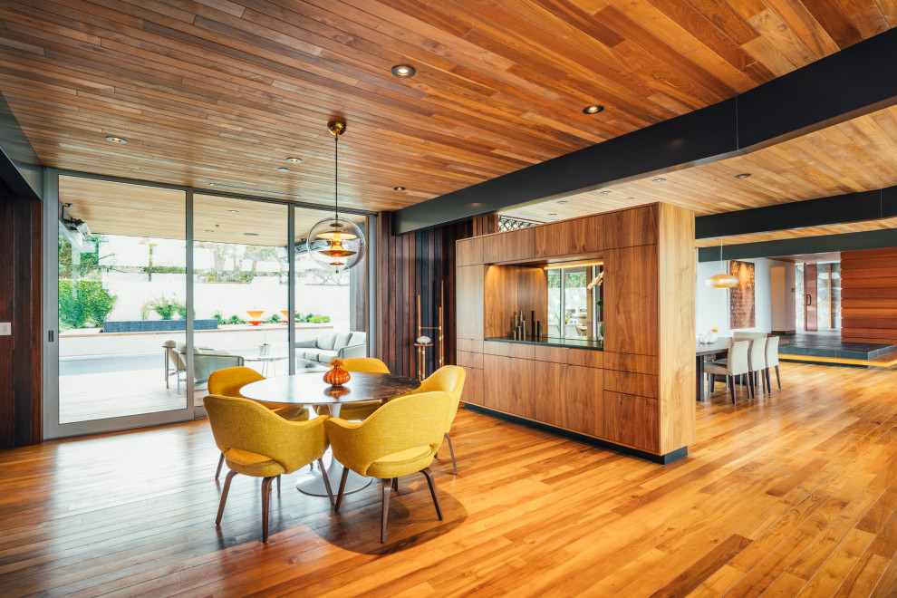 Ispirazione per una sala da pranzo aperta verso il soggiorno minimalista con pavimento in legno massello medio, travi a vista e soffitto in legno