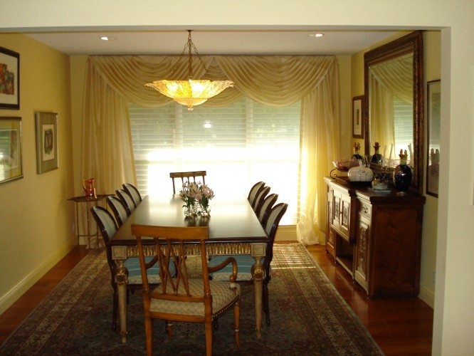 Immagine di una sala da pranzo chic chiusa e di medie dimensioni con pareti gialle, parquet scuro, nessun camino e pavimento marrone