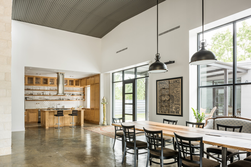 Idee per una grande sala da pranzo aperta verso la cucina industriale con pareti bianche e pavimento in cemento