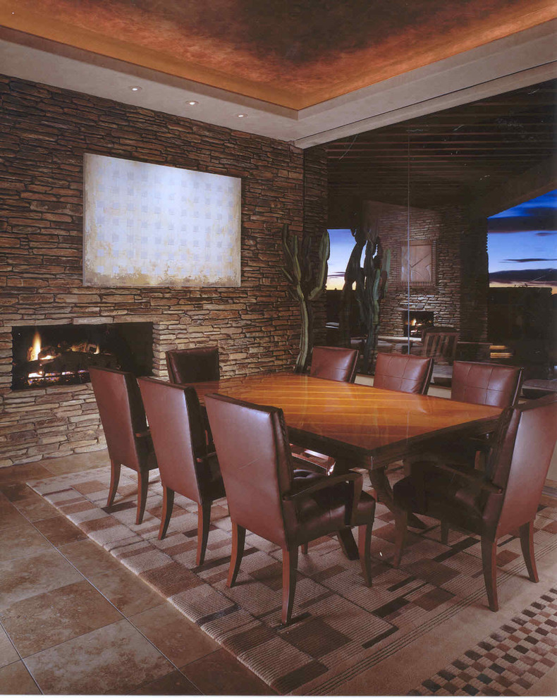 Idée de décoration pour une grande salle à manger sud-ouest américain fermée avec un mur beige, un sol en travertin, une cheminée double-face et un manteau de cheminée en pierre.