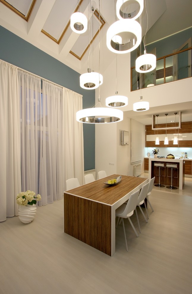 Réalisation d'une salle à manger ouverte sur la cuisine design avec un mur bleu.
