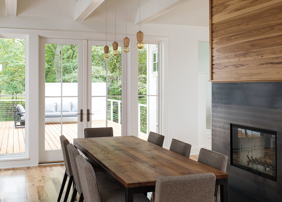 Foto de comedor contemporáneo de tamaño medio con paredes blancas, suelo de madera clara, todas las chimeneas, marco de chimenea de metal y suelo beige