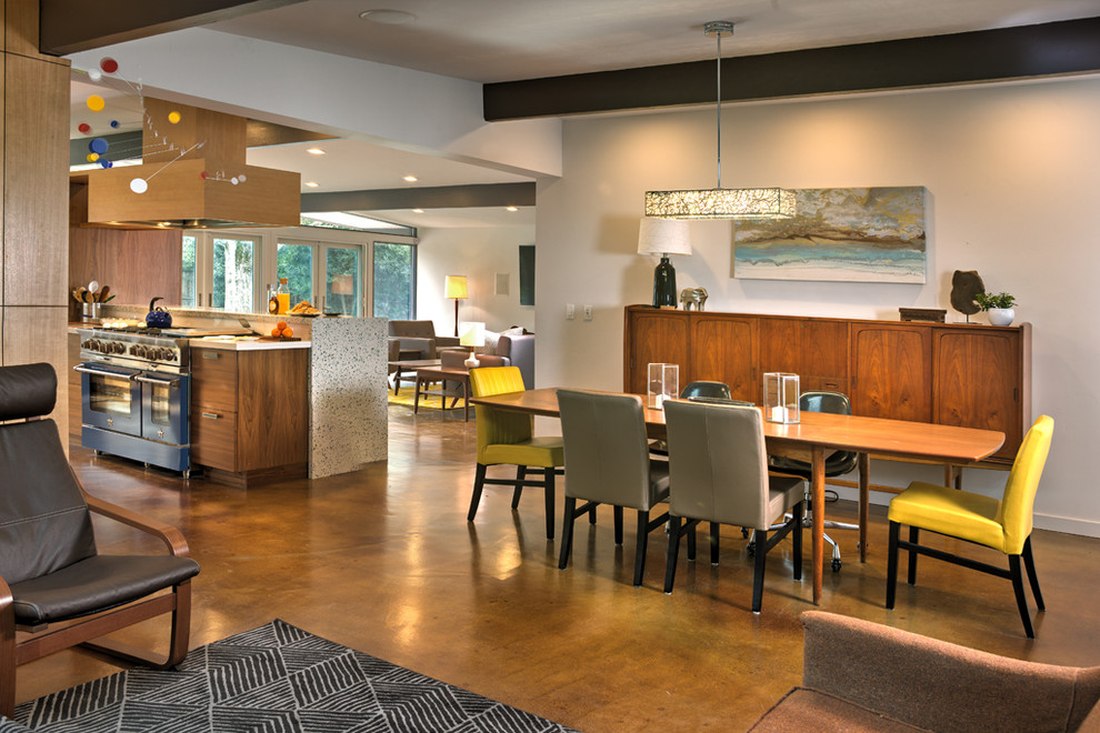 На фото: кухня-столовая среднего размера в стиле модернизм с белыми стенами, бетонным полом, стандартным камином и фасадом камина из кирпича