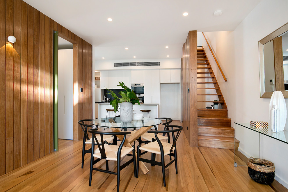 Example of a trendy medium tone wood floor kitchen/dining room combo design in Sydney with white walls and no fireplace