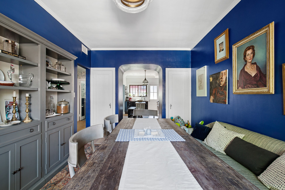 Cette photo montre une salle à manger éclectique fermée avec un mur bleu et aucune cheminée.