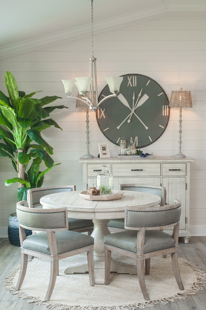 Coastal dining room in Jacksonville with beige floors, beige walls and feature lighting.