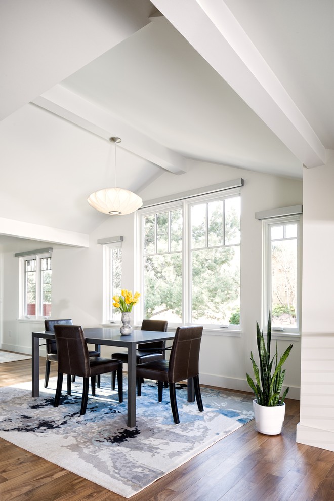 Esempio di una sala da pranzo aperta verso la cucina chic di medie dimensioni con pareti bianche, pavimento in legno massello medio e pavimento marrone