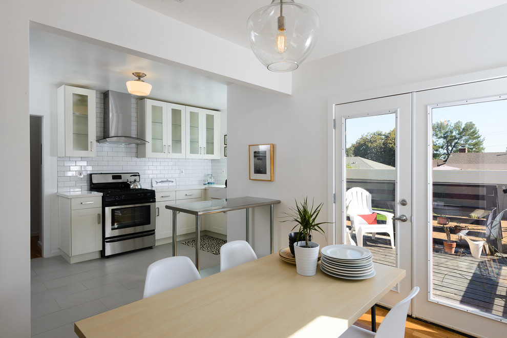 Immagine di una piccola sala da pranzo aperta verso la cucina contemporanea con pareti bianche e parquet chiaro