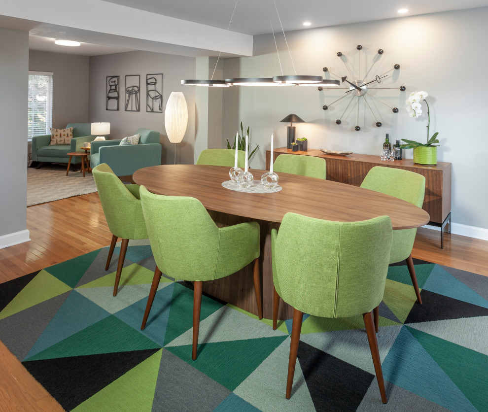 Foto di una grande sala da pranzo aperta verso la cucina minimalista con pareti grigie, parquet chiaro e pavimento marrone