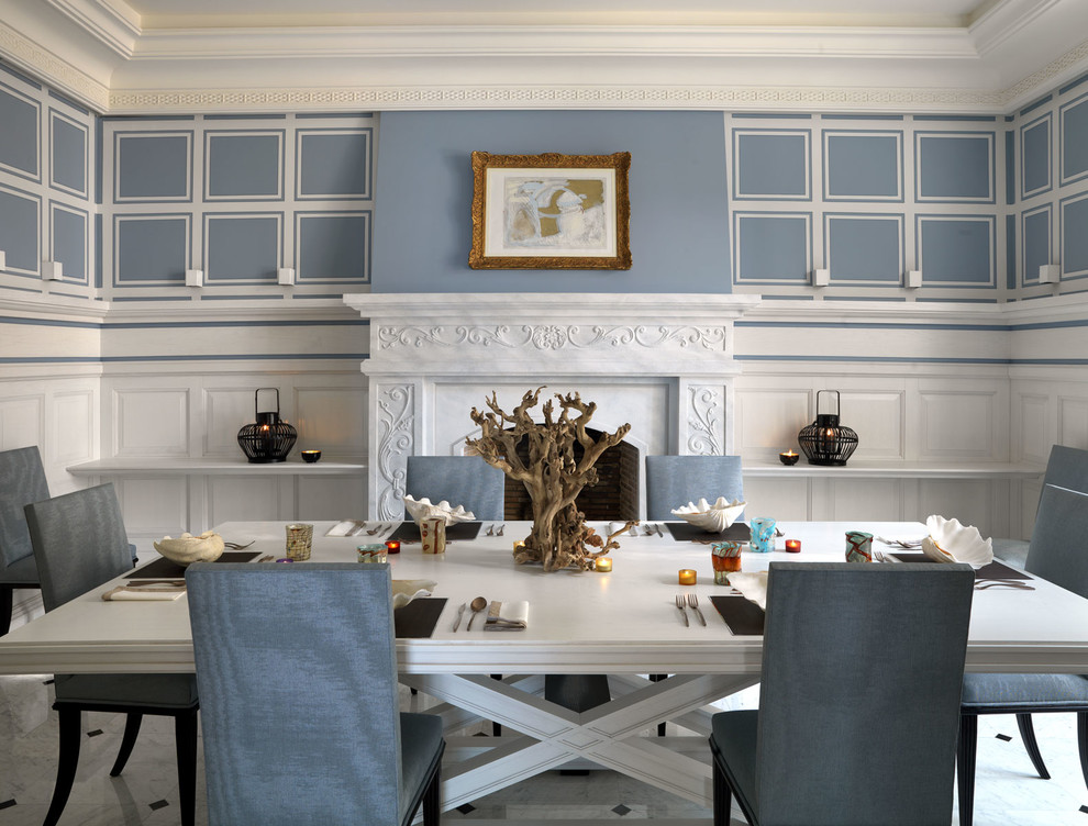 Immagine di una sala da pranzo chic chiusa e di medie dimensioni con pareti blu, pavimento in marmo, camino classico e cornice del camino in pietra