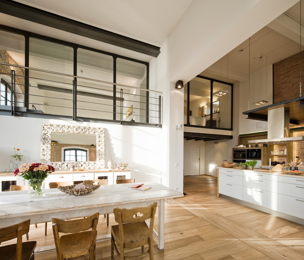 Foto di una sala da pranzo aperta verso il soggiorno shabby-chic style con parquet chiaro