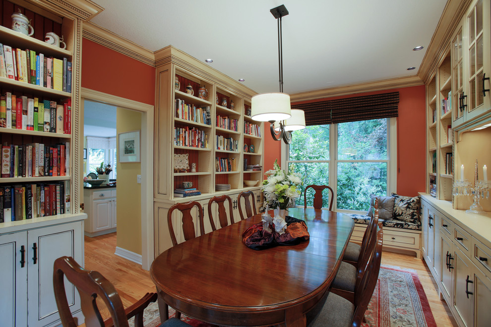 Immagine di una sala da pranzo classica chiusa e di medie dimensioni con pareti arancioni, pavimento in legno massello medio e nessun camino