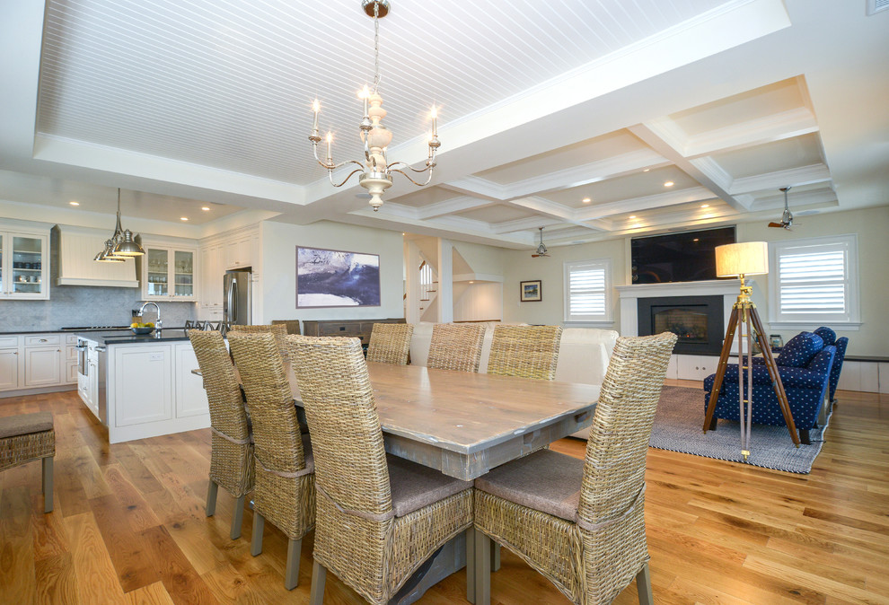 Cette image montre une grande salle à manger ouverte sur le salon design avec un mur blanc et un sol en bois brun.