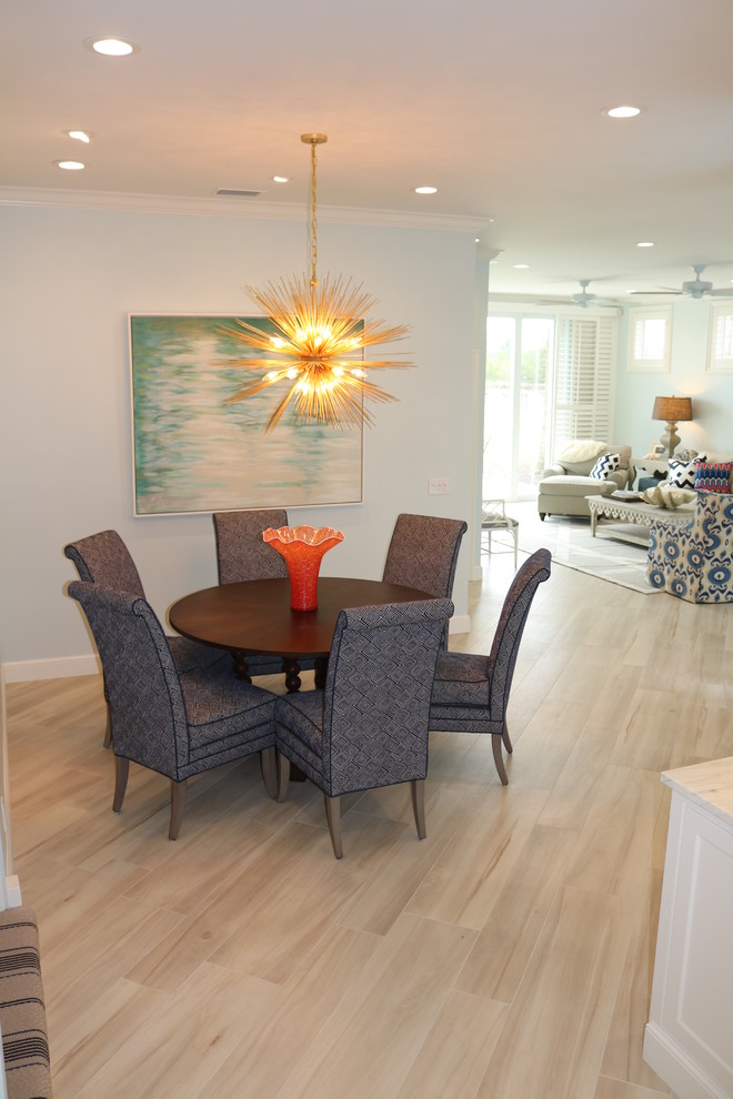 Cette image montre une salle à manger ouverte sur le salon design de taille moyenne avec un mur bleu, un sol en carrelage de porcelaine, aucune cheminée, un sol beige et éclairage.