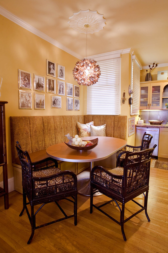 Foto di una sala da pranzo aperta verso la cucina tradizionale con pareti gialle e pavimento in legno massello medio