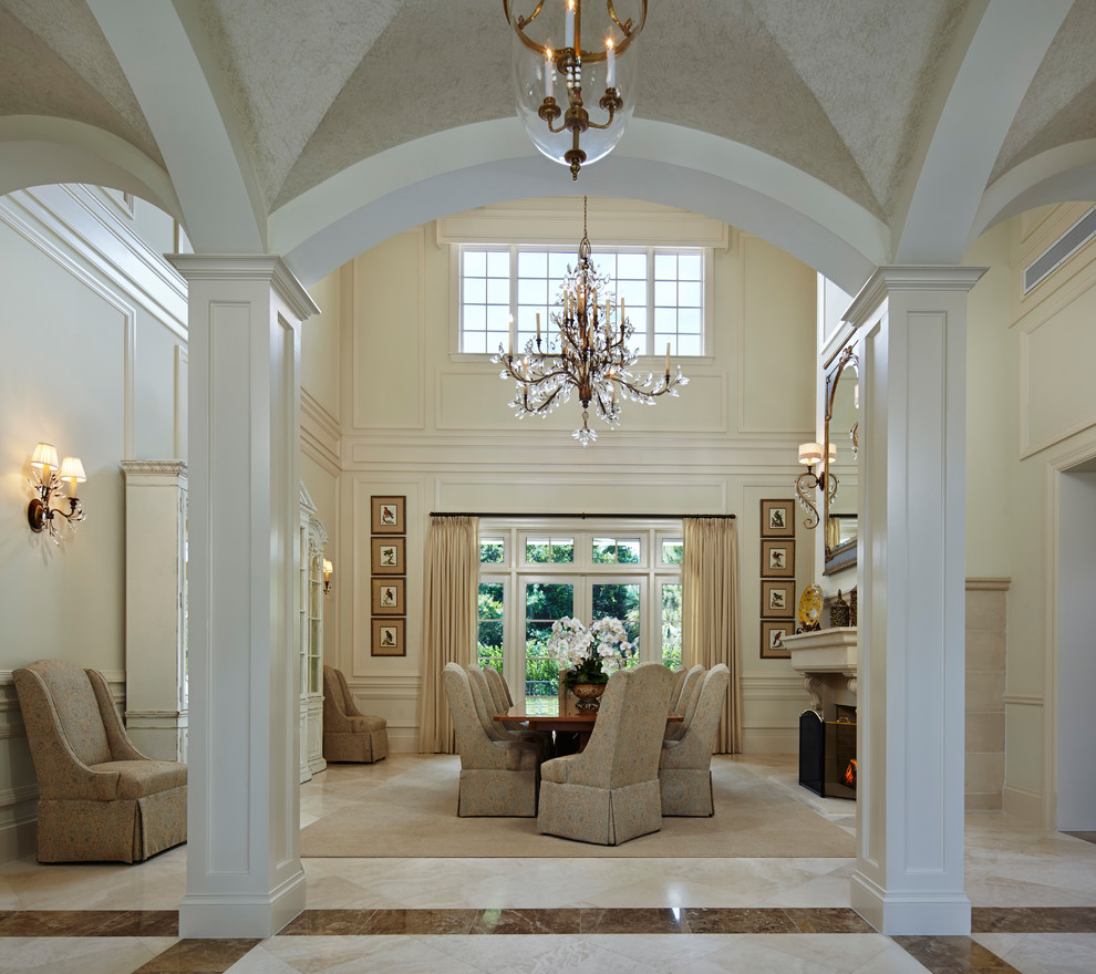 Immagine di una sala da pranzo classica con pareti bianche, pavimento in marmo, cornice del camino in cemento, pavimento bianco e camino classico