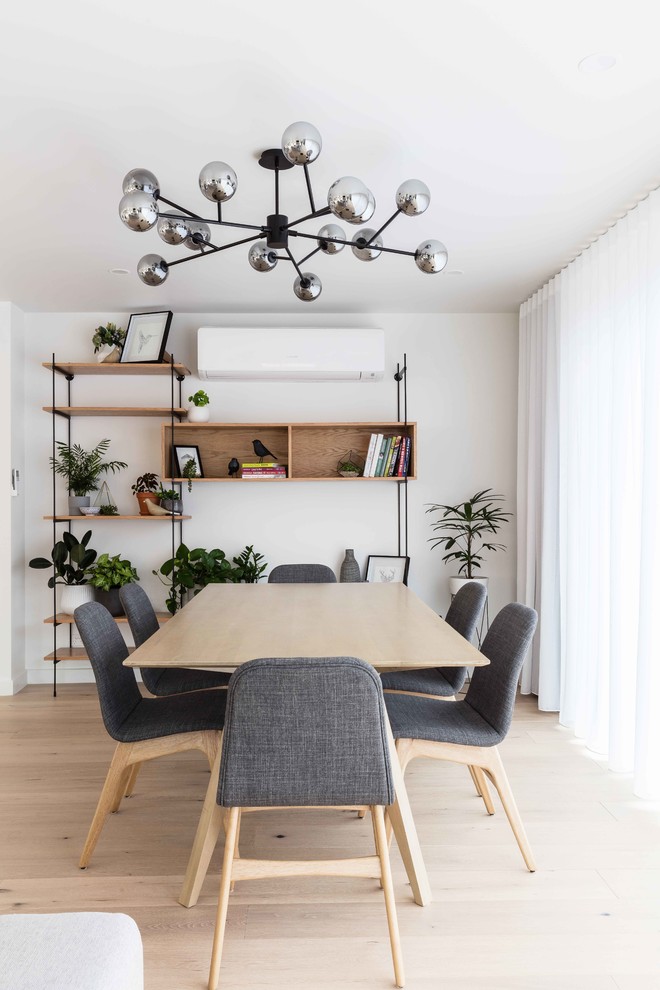Esempio di una sala da pranzo aperta verso la cucina scandinava con pareti bianche, parquet chiaro e pavimento beige