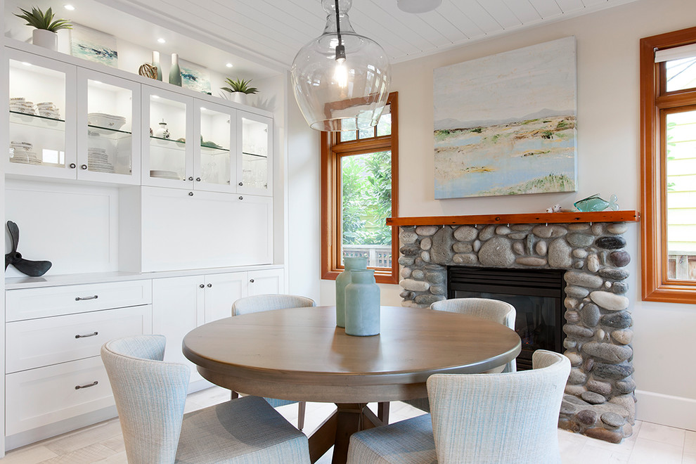Exemple d'une salle à manger ouverte sur la cuisine bord de mer de taille moyenne avec un sol en carrelage de porcelaine, une cheminée standard et un manteau de cheminée en pierre.