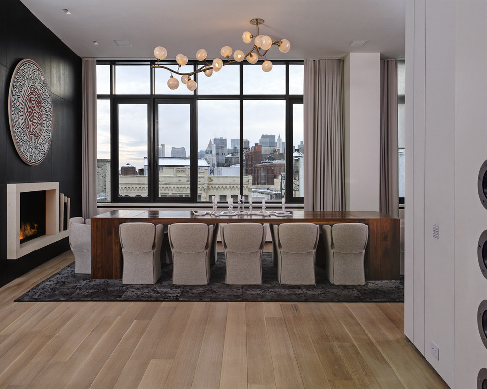 Example of a minimalist light wood floor dining room design in New York with black walls and a standard fireplace
