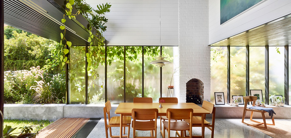 Offenes, Mittelgroßes Modernes Esszimmer mit weißer Wandfarbe, Betonboden, Kamin, Kaminumrandung aus Backstein und grauem Boden in Brisbane