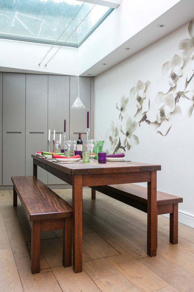 Contemporary dining room in London with white walls, medium hardwood flooring and brown floors.