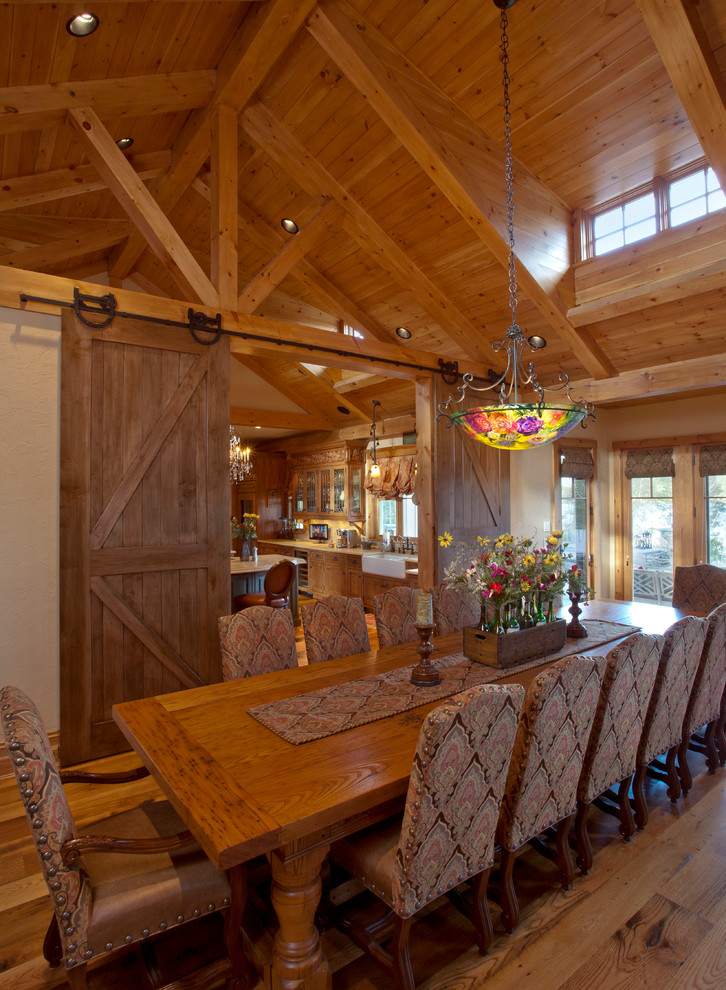 Exemple d'une très grande salle à manger ouverte sur la cuisine montagne avec un mur marron, un sol en bois brun et aucune cheminée.