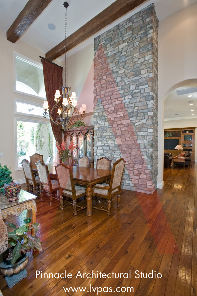 Cette photo montre une très grande salle à manger ouverte sur le salon méditerranéenne avec un mur beige, un sol en bois brun, une cheminée standard, un manteau de cheminée en béton, un sol marron et poutres apparentes.