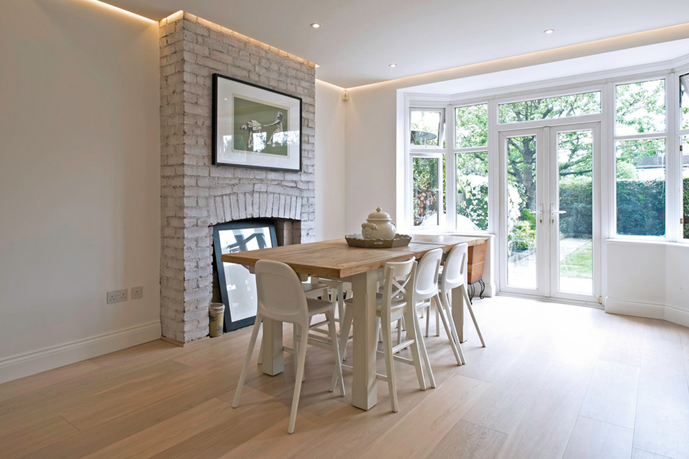 Design ideas for a medium sized contemporary kitchen/dining room in London with white walls, ceramic flooring, a standard fireplace, a brick fireplace surround and beige floors.