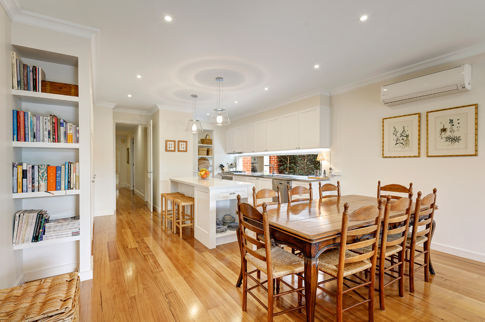 Exemple d'une grande salle à manger ouverte sur la cuisine chic avec un mur blanc et un sol en bois brun.