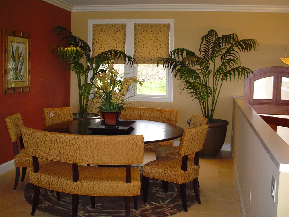 Immagine di una sala da pranzo aperta verso il soggiorno tropicale con pareti rosse e pavimento in pietra calcarea