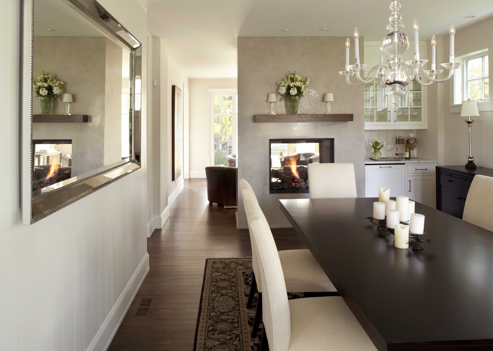 Источник вдохновения для домашнего уюта: отдельная столовая в классическом стиле с белыми стенами, темным паркетным полом, двусторонним камином, фасадом камина из штукатурки и коричневым полом
