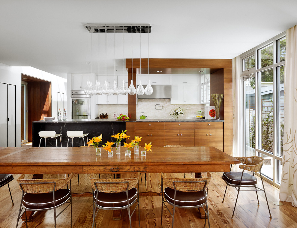 Esempio di una sala da pranzo aperta verso la cucina minimalista con pareti bianche e pavimento in legno massello medio