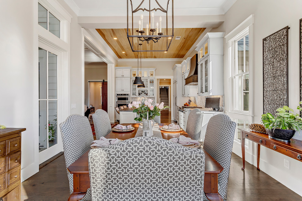 Immagine di una grande sala da pranzo aperta verso la cucina country con pareti beige, parquet scuro e pavimento marrone