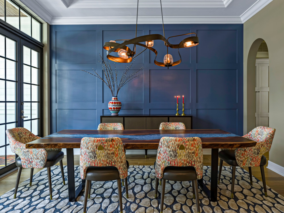 На фото: отдельная столовая в стиле неоклассика (современная классика) с синими стенами, паркетным полом среднего тона, коричневым полом и панелями на части стены