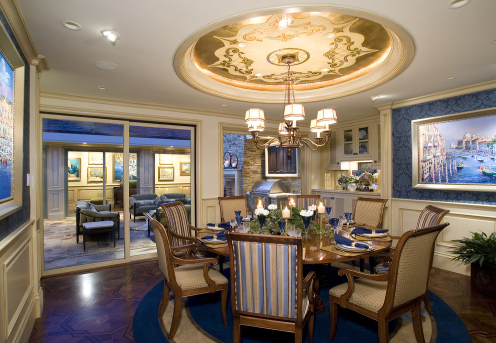 Cette image montre une grande salle à manger ouverte sur la cuisine traditionnelle avec un mur bleu, parquet foncé, aucune cheminée et un sol marron.