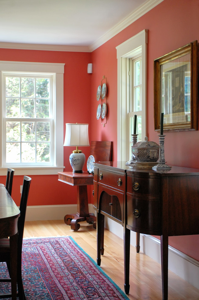Cette photo montre une salle à manger chic fermée et de taille moyenne avec un mur rouge, parquet clair et aucune cheminée.