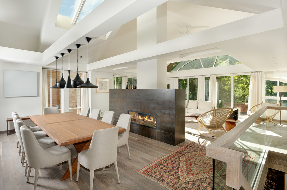Пример оригинального дизайна: кухня-столовая среднего размера в современном стиле с белыми стенами, светлым паркетным полом, двусторонним камином и фасадом камина из металла