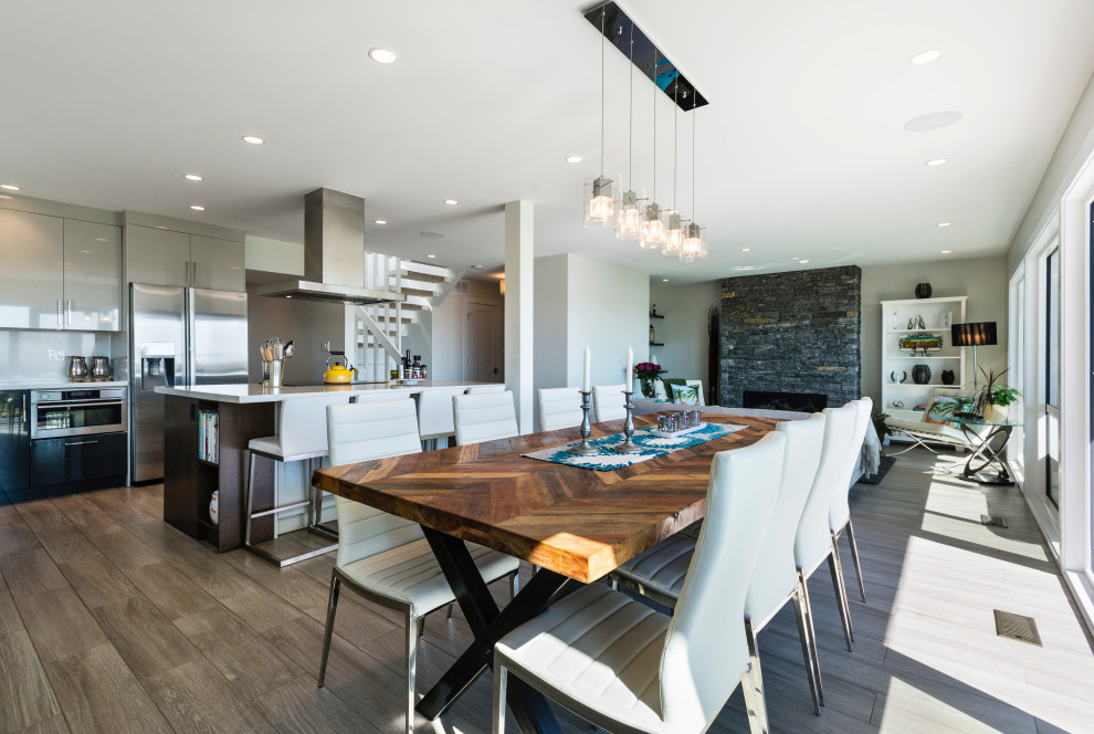 Mittelgroße Moderne Wohnküche mit beiger Wandfarbe, braunem Holzboden, Kamin, Kaminumrandung aus Stein und braunem Boden in Sonstige