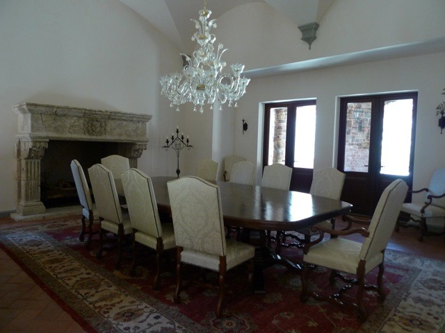 Esempio di una sala da pranzo aperta verso la cucina mediterranea di medie dimensioni con camino classico, cornice del camino in pietra, pareti beige e pavimento in pietra calcarea