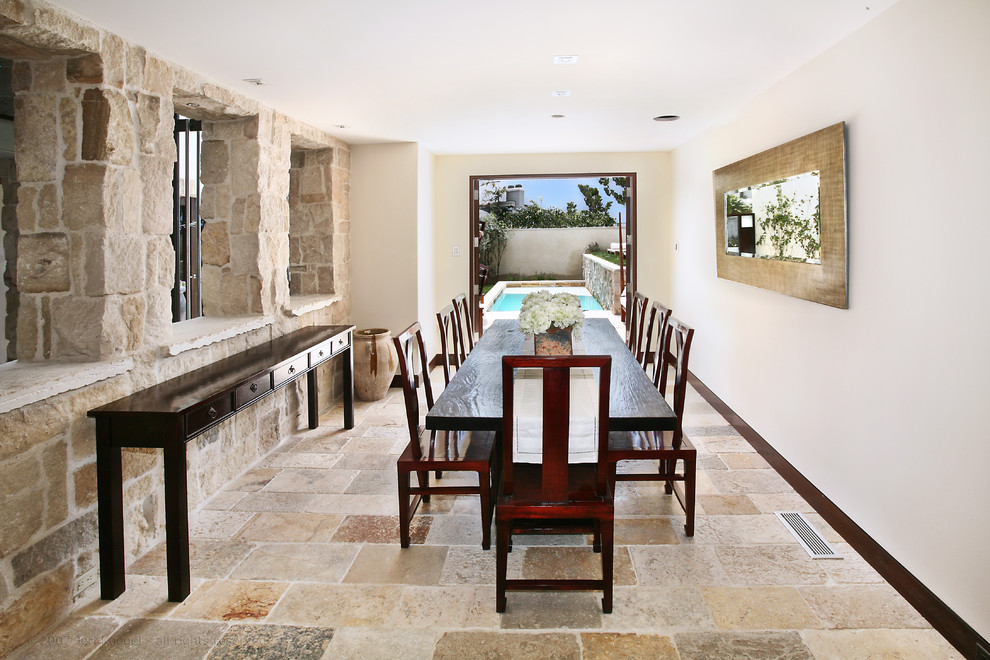Cette image montre une salle à manger ouverte sur la cuisine méditerranéenne de taille moyenne avec un mur beige, un sol en calcaire et un sol beige.