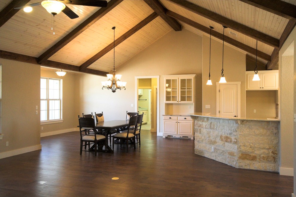 Idée de décoration pour une salle à manger ouverte sur la cuisine tradition de taille moyenne avec un mur beige, parquet foncé, une cheminée d'angle, un manteau de cheminée en pierre et un sol marron.
