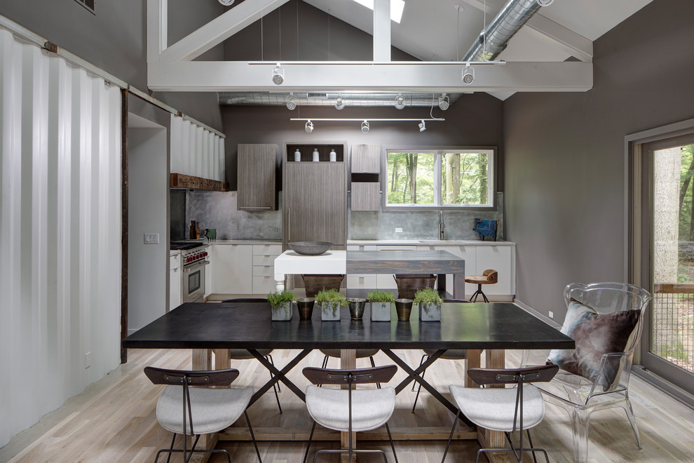 Inspiration pour une salle à manger ouverte sur la cuisine design avec un mur gris et parquet clair.