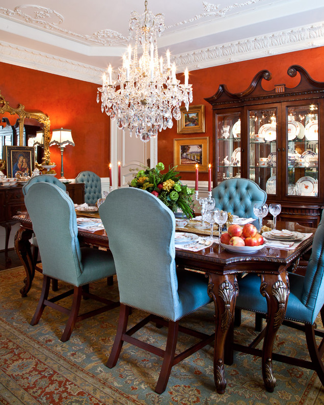 Cette image montre une salle à manger traditionnelle fermée et de taille moyenne avec parquet foncé, un mur orange et éclairage.