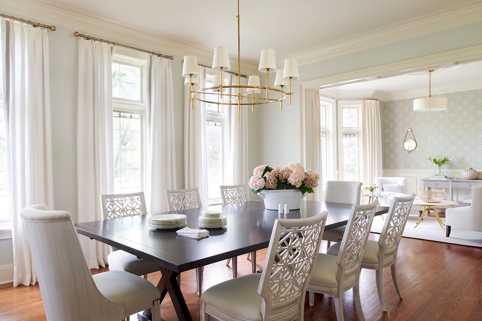 Aménagement d'une salle à manger ouverte sur le salon classique avec un mur bleu, un sol en bois brun et aucune cheminée.