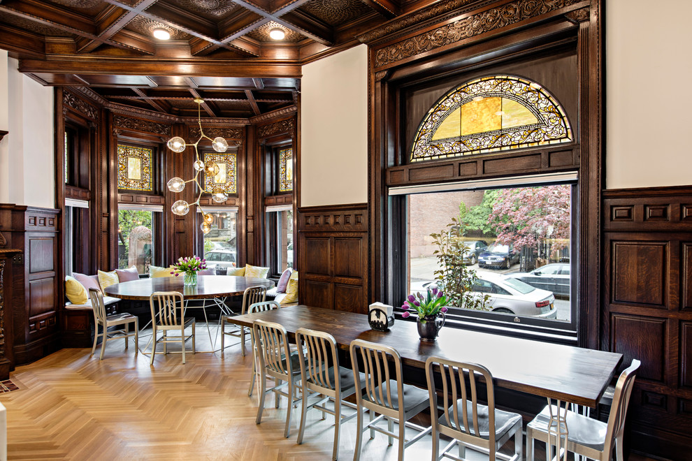 Photo of a large traditional kitchen/dining room in New York with white walls, light hardwood flooring, a standard fireplace, a tiled fireplace surround and beige floors.