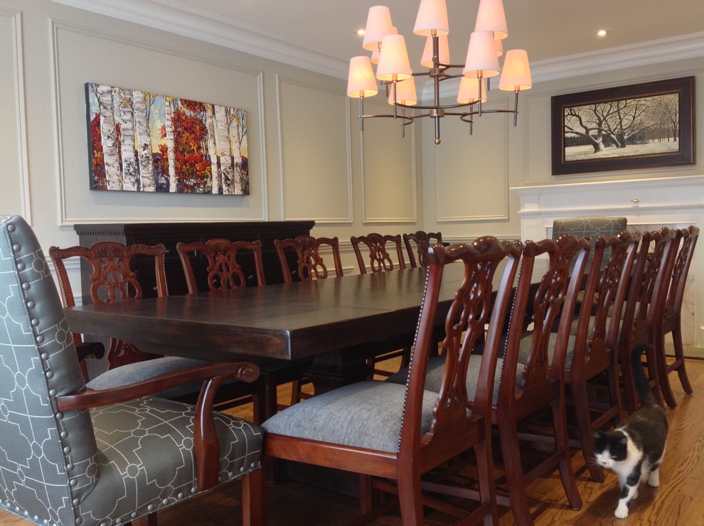 Inspiration for a large traditional enclosed dining room in Montreal with grey walls, medium hardwood flooring, a standard fireplace and a wooden fireplace surround.