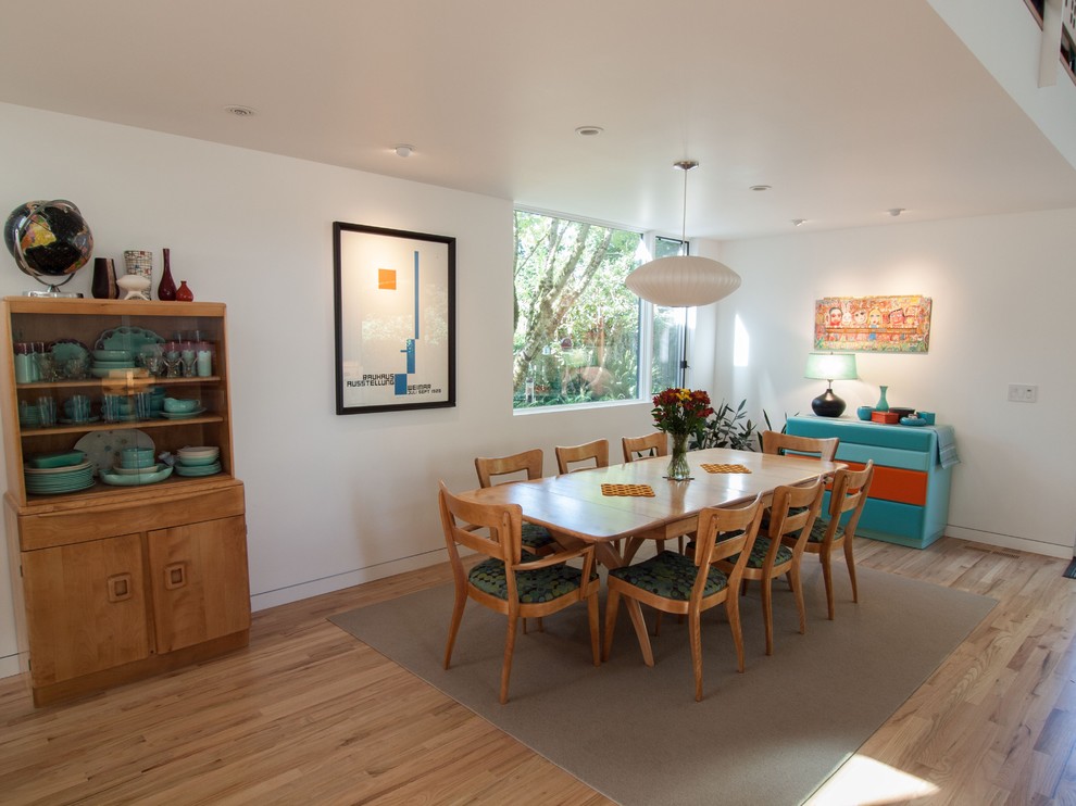 Example of a trendy medium tone wood floor dining room design in Portland with white walls