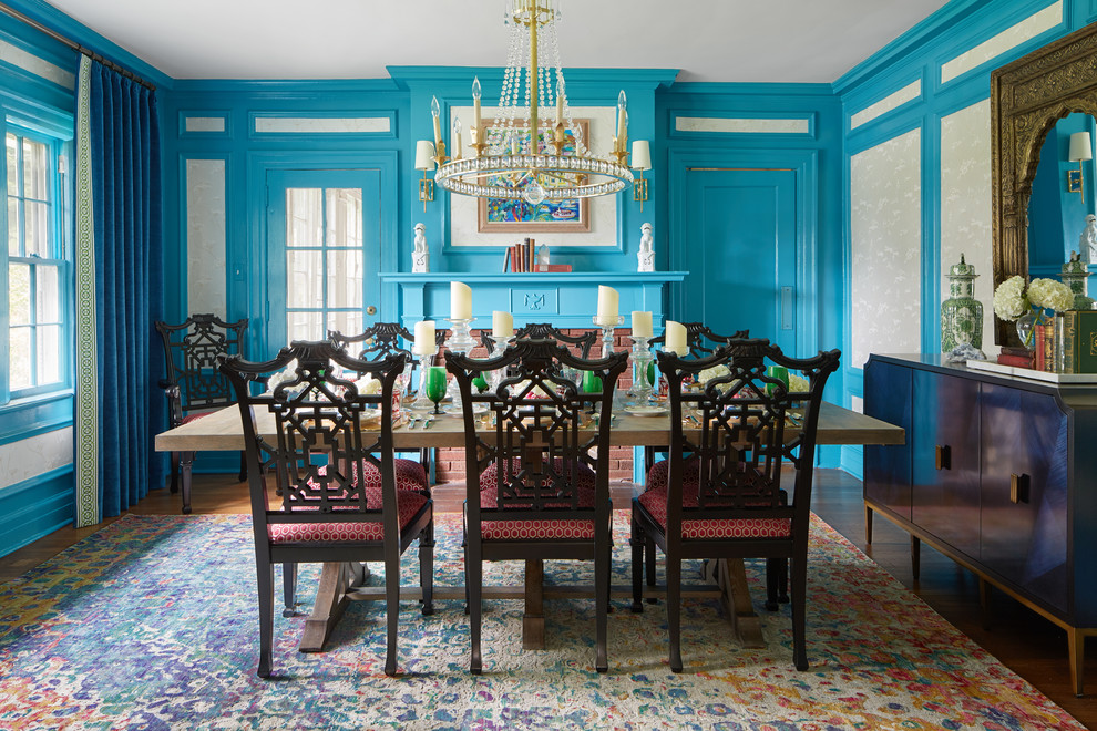 Inspiration pour une salle à manger traditionnelle fermée et de taille moyenne avec un mur bleu, un sol en bois brun, une cheminée standard, un manteau de cheminée en brique et un sol marron.