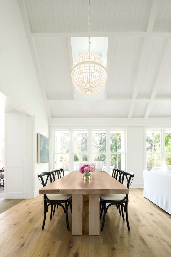 Immagine di una sala da pranzo aperta verso il soggiorno classica con pareti bianche e parquet chiaro