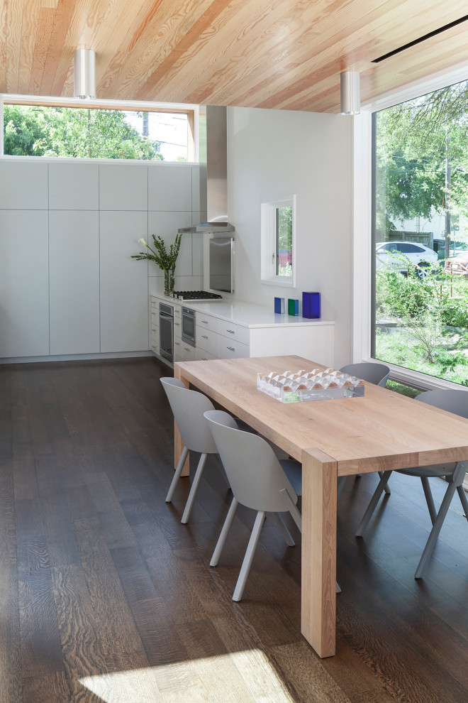 Réalisation d'une grande salle à manger ouverte sur la cuisine minimaliste avec un mur blanc, un sol en bois brun, un sol marron et un plafond en bois.